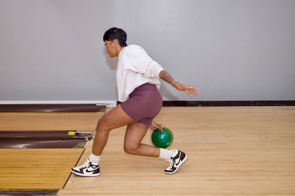 A participant bowling with a green ball.