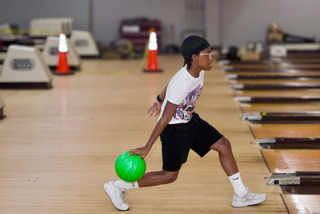 A young participant releasing a bowling ball.